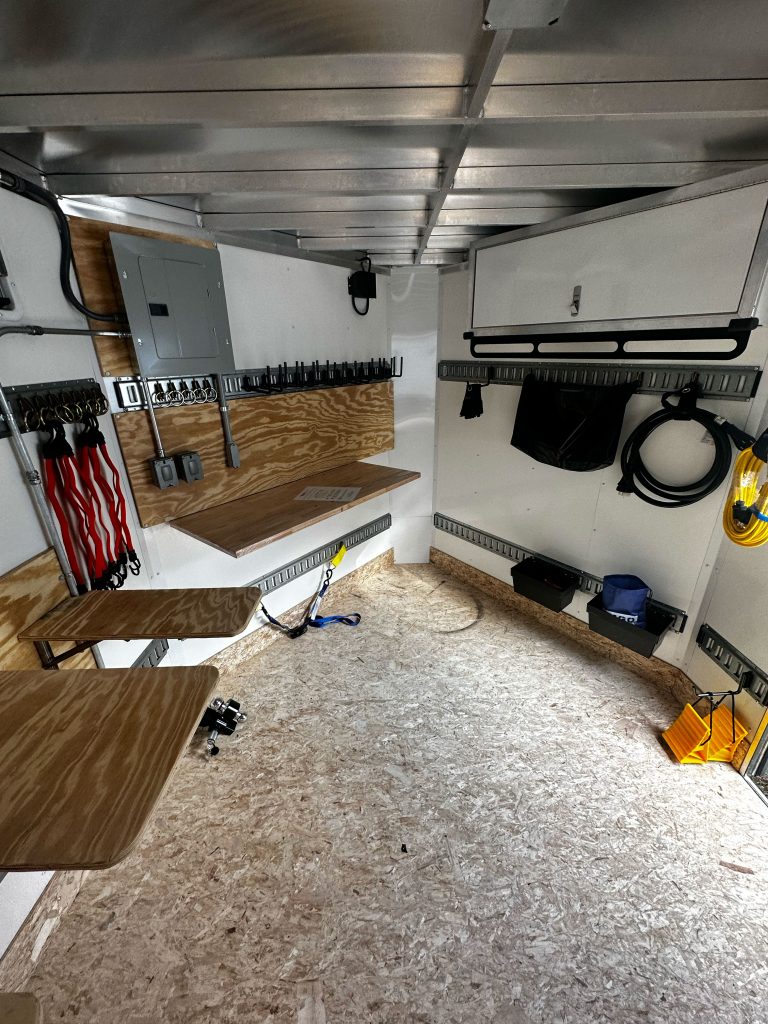 A small trailer work area filled with various tools and an electrical box