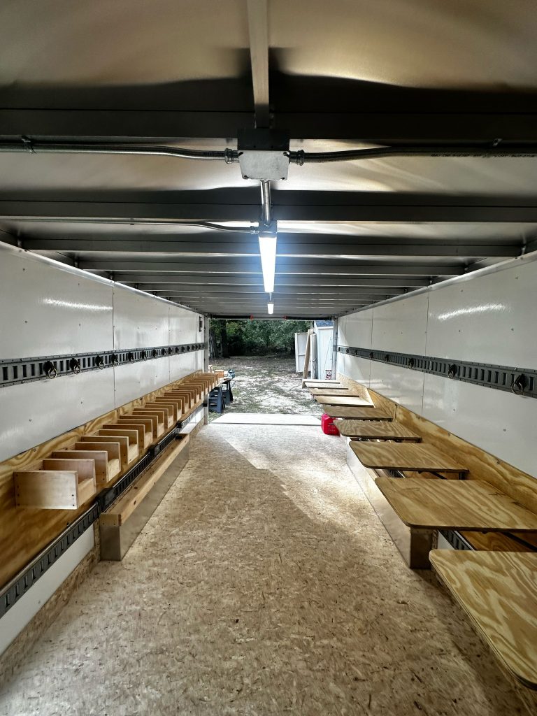 A custom trailer featuring wooden benches inside and fluorescent lighting