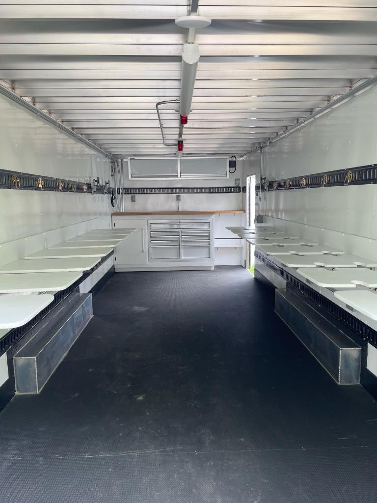 A large white custom trailer filled with multiple tables